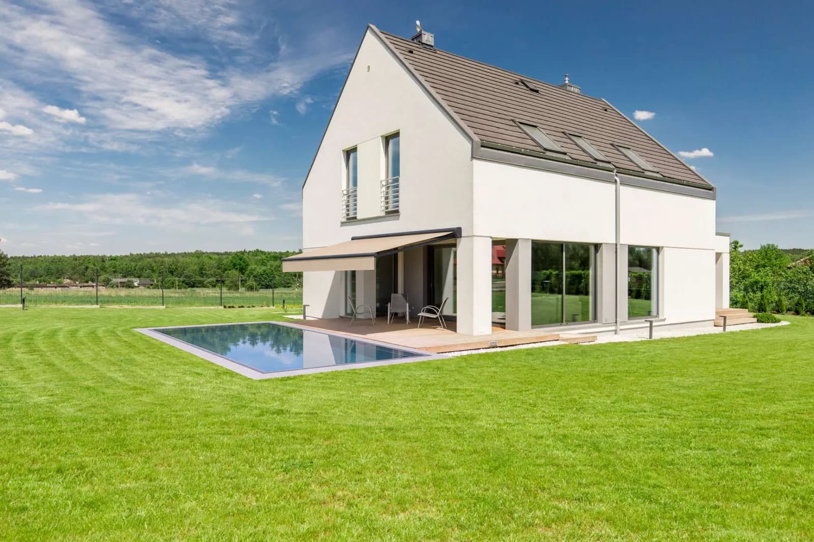 Jardin avec un store banne au-dessus de la terrasse et un bassin à débordement, 6 × 3 m, revêtement gris clair, intégré dans le studio